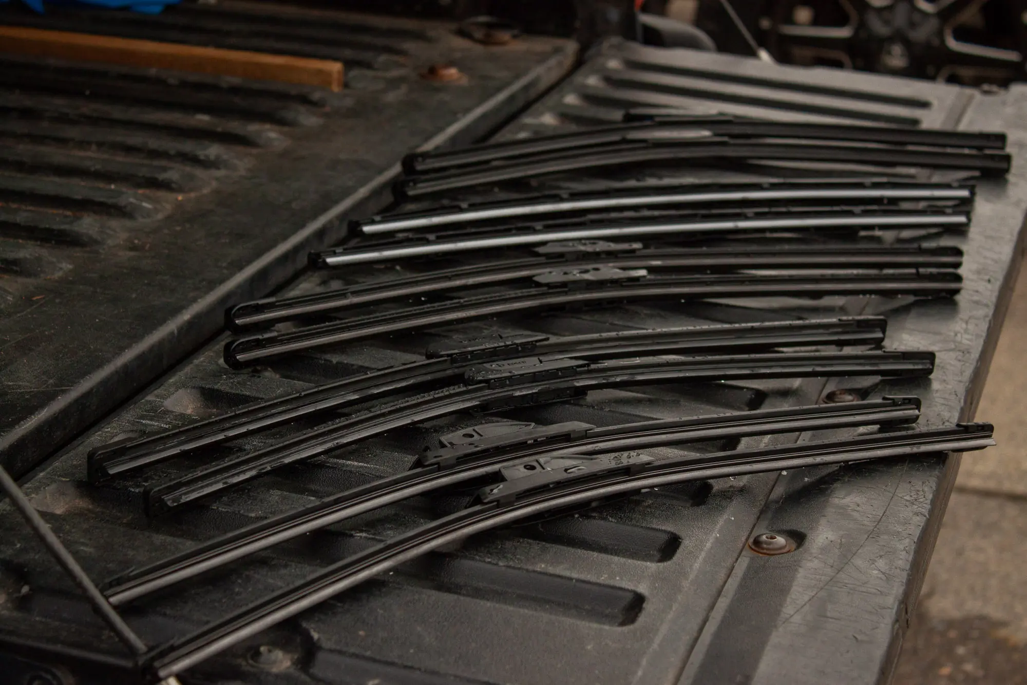 five sets of wiper blades laid on a truck tailgate ready to be tested