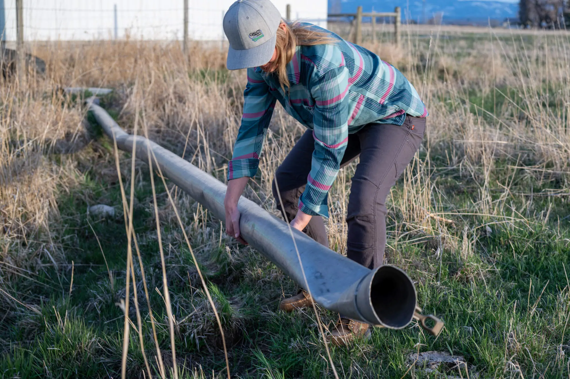 The author bends down to move irrigation pipe in the Dovetail Britt Pants