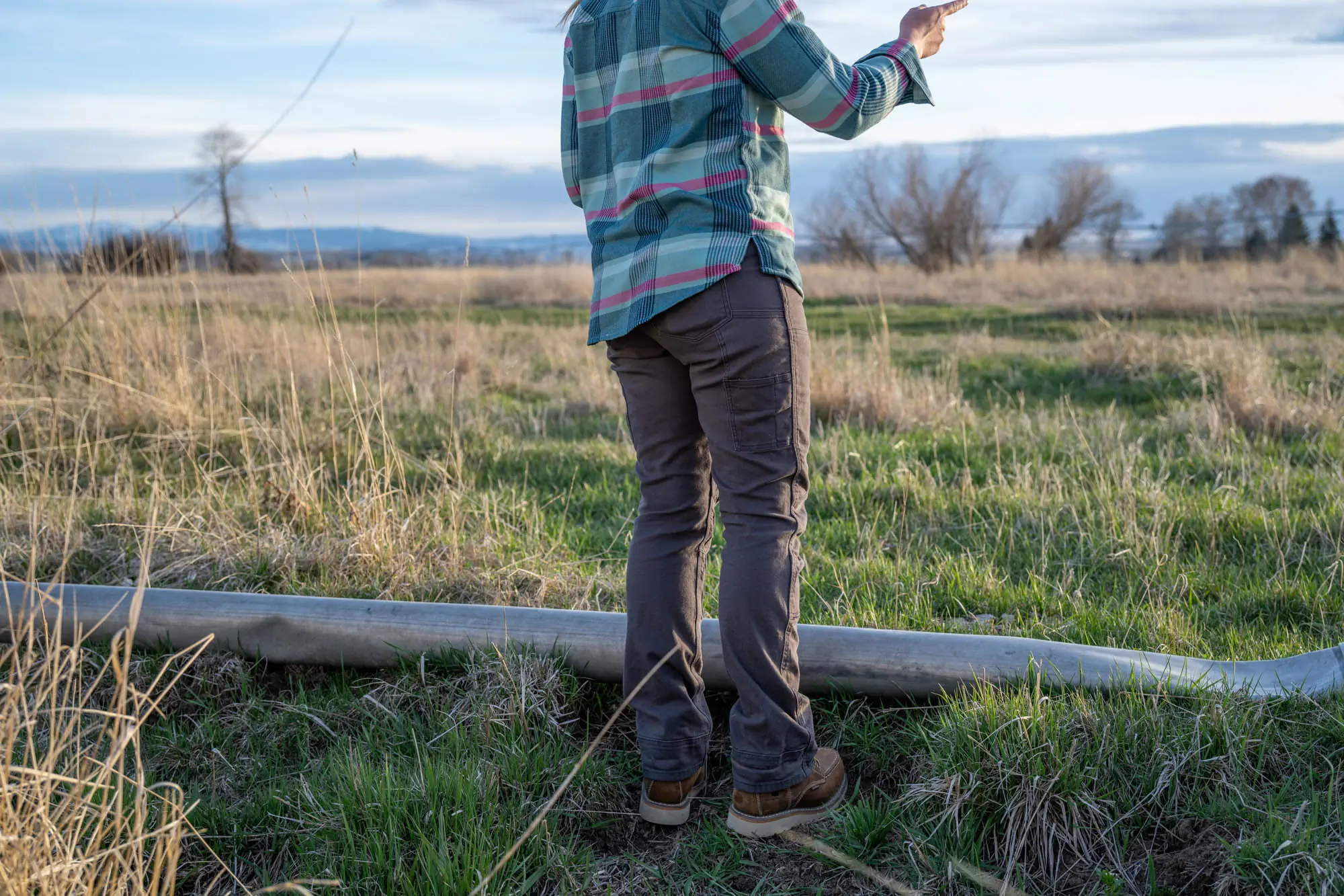 A woman wearing the Dovetail Britt Utility pants surveys a field