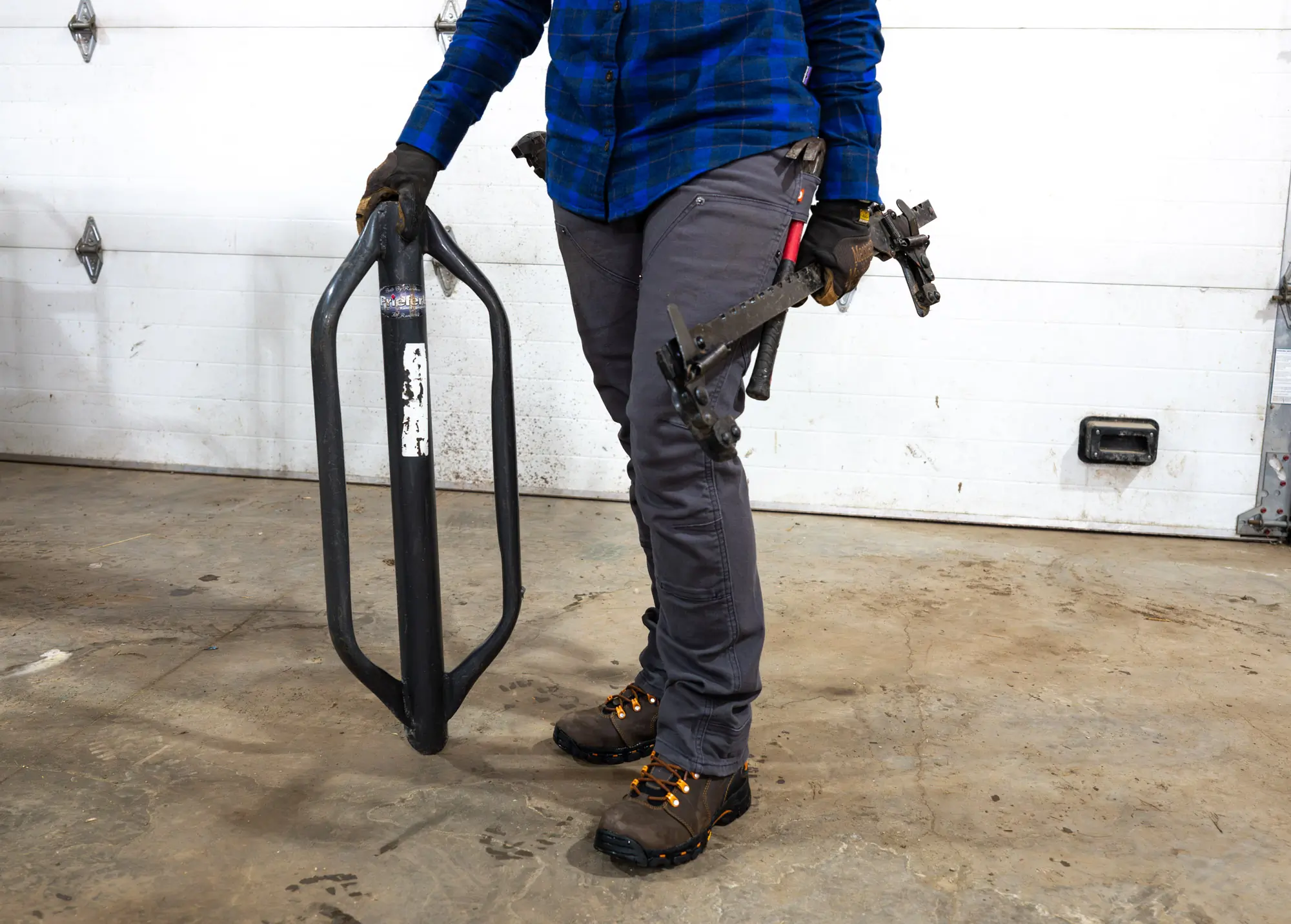 A farmer holds all of the tools necessary to mend fences