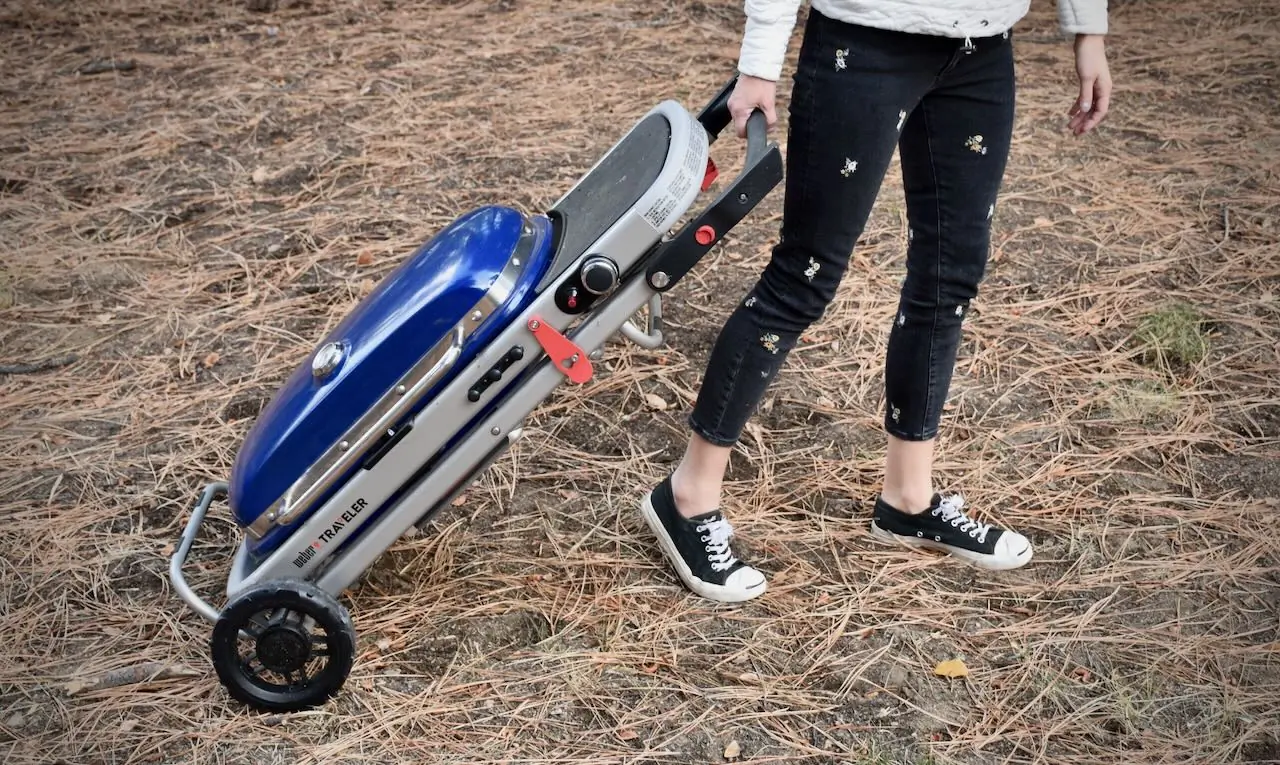 showing the weber traveler portable grill folded up and rolling away
