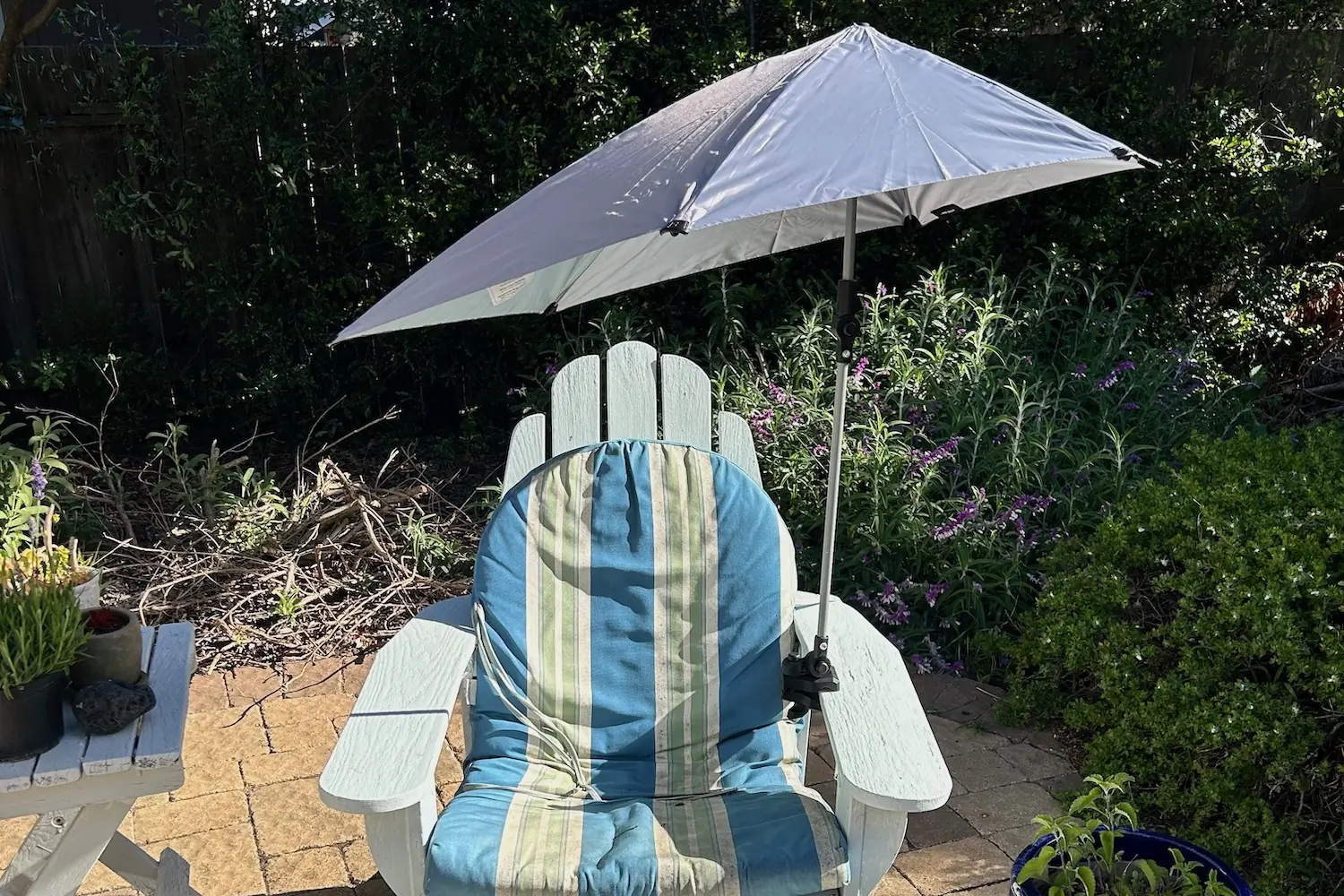 The Sport-Brella Versa Brella clamped to the arm of a chair in the backward garden