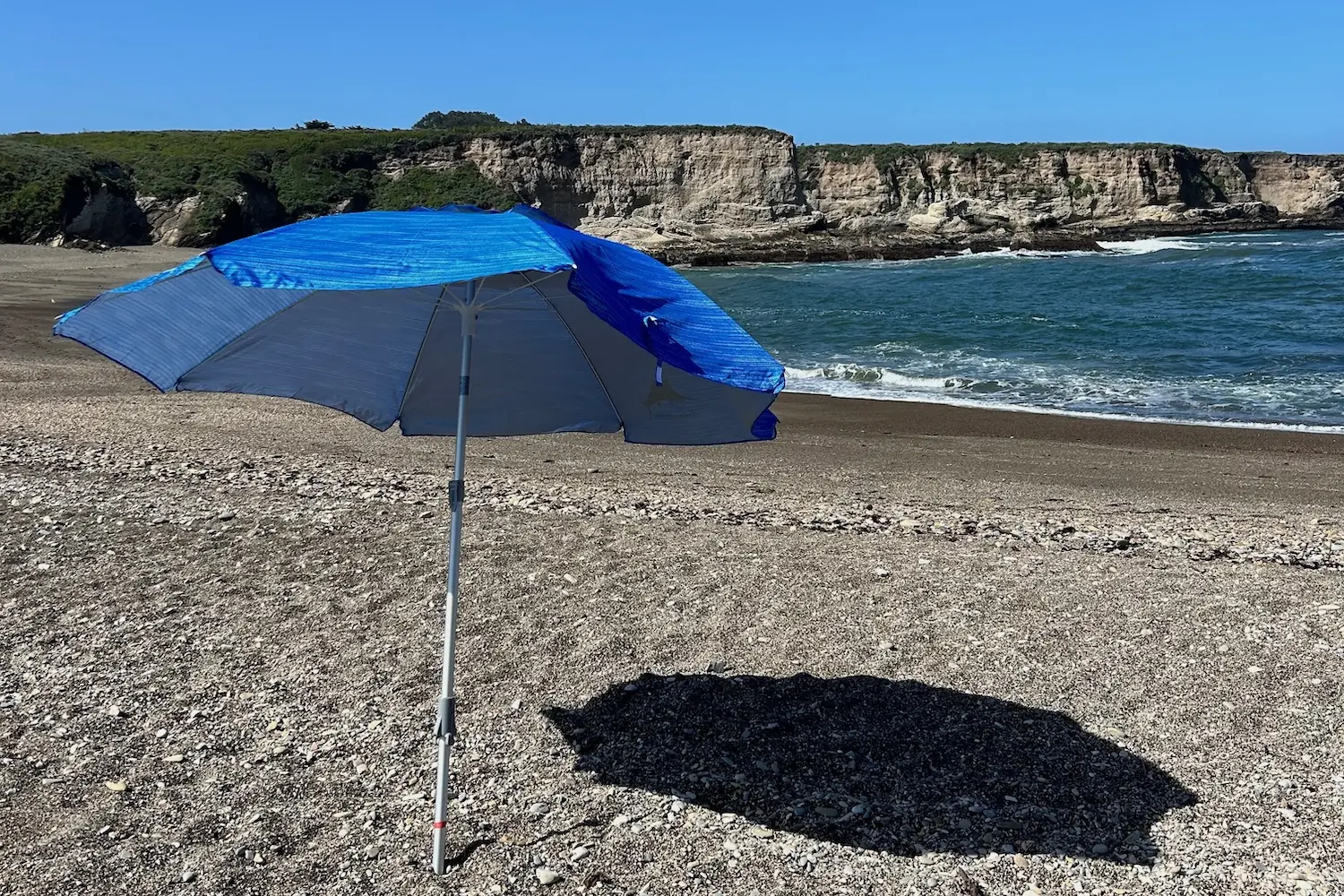 The Tommy Bahama Beach Umbrella being affected by a light breeze while set up at the beach