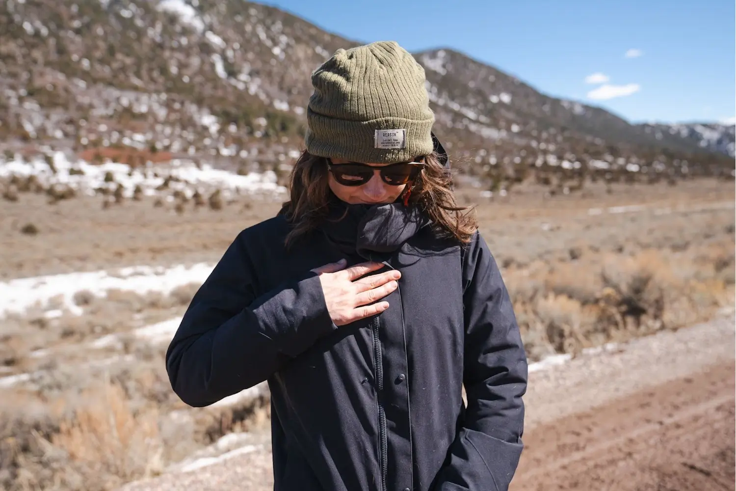 Woman wearing Patera Parka, stands amidst windy weather