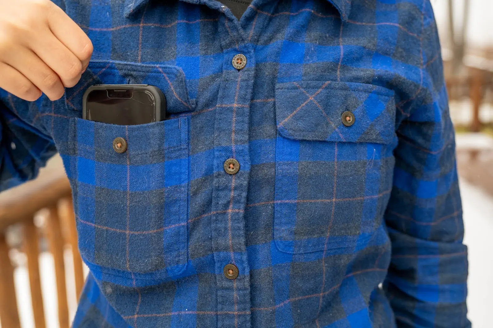 a man holding and showing his phone stored in the front pocket of a patagonia fjord flannel