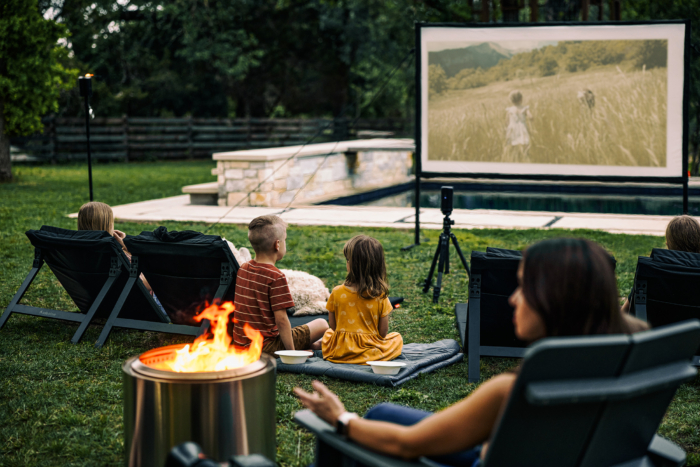 family watching backyard movie next to solo stove fire pit