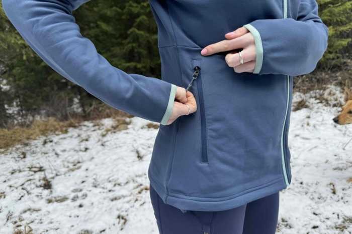 woman unzipping the zip pocket on the rei co-op flash hyperstretch fleece jacket