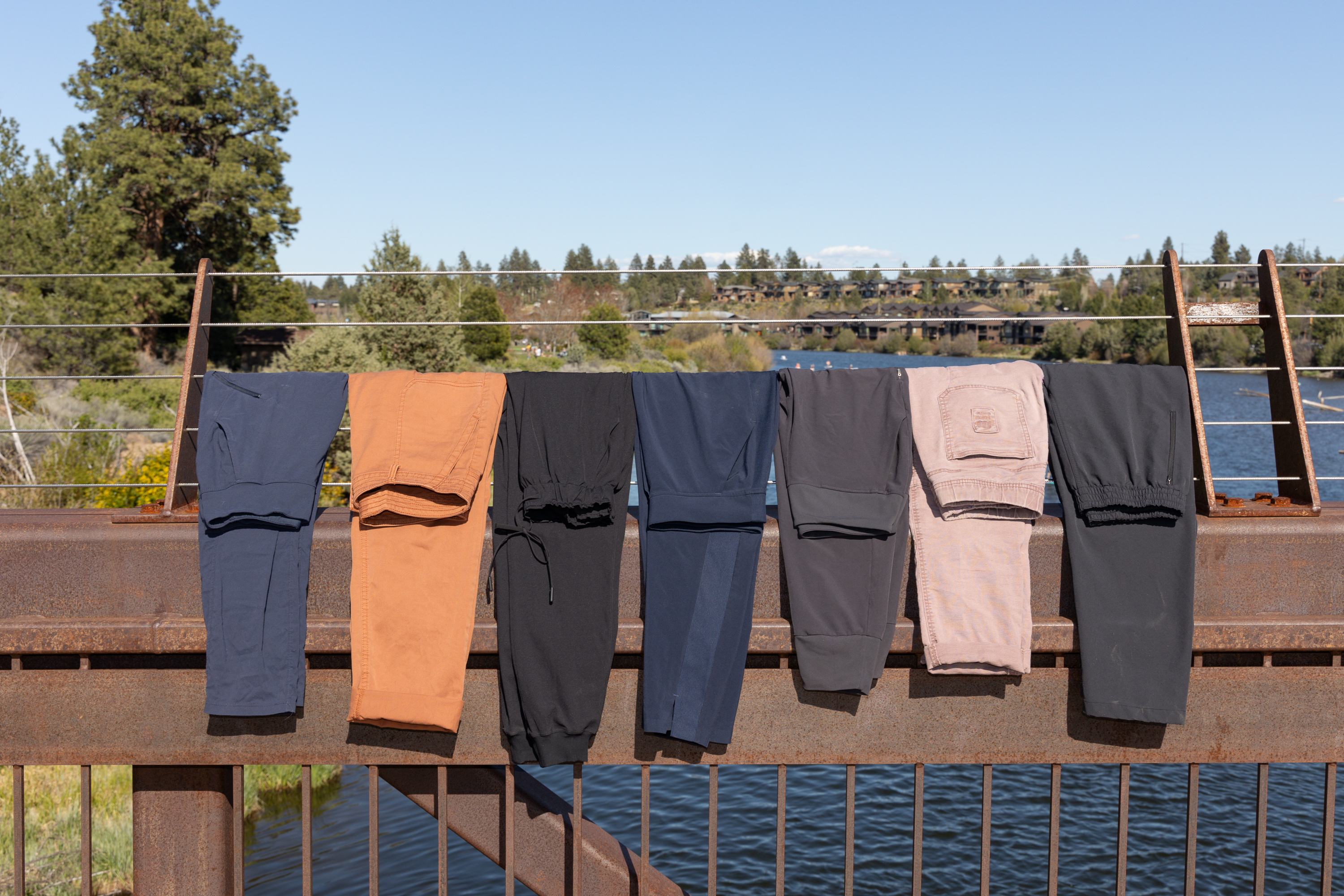 A line of seven pants hung on a bridge railing