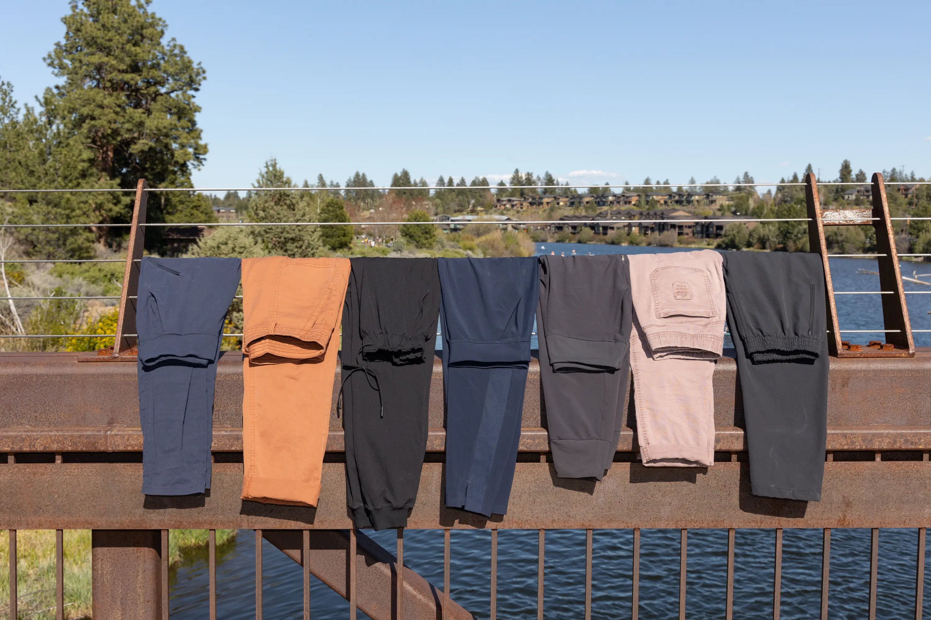 A line of seven pants hung on a bridge railing