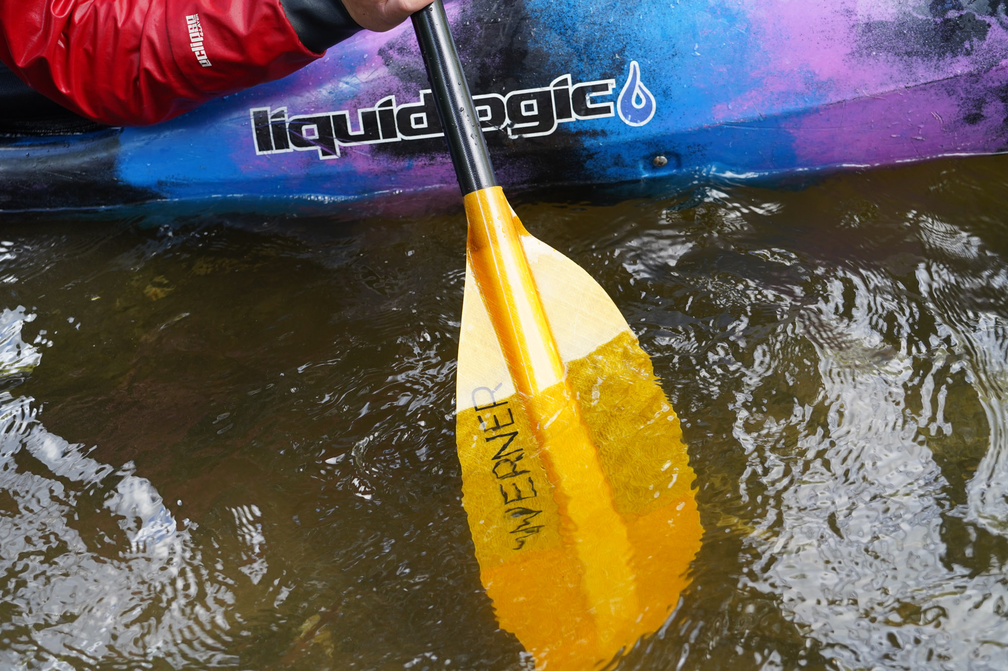 The Sherpa paddle being dipped in the river, showing the blade shape and size