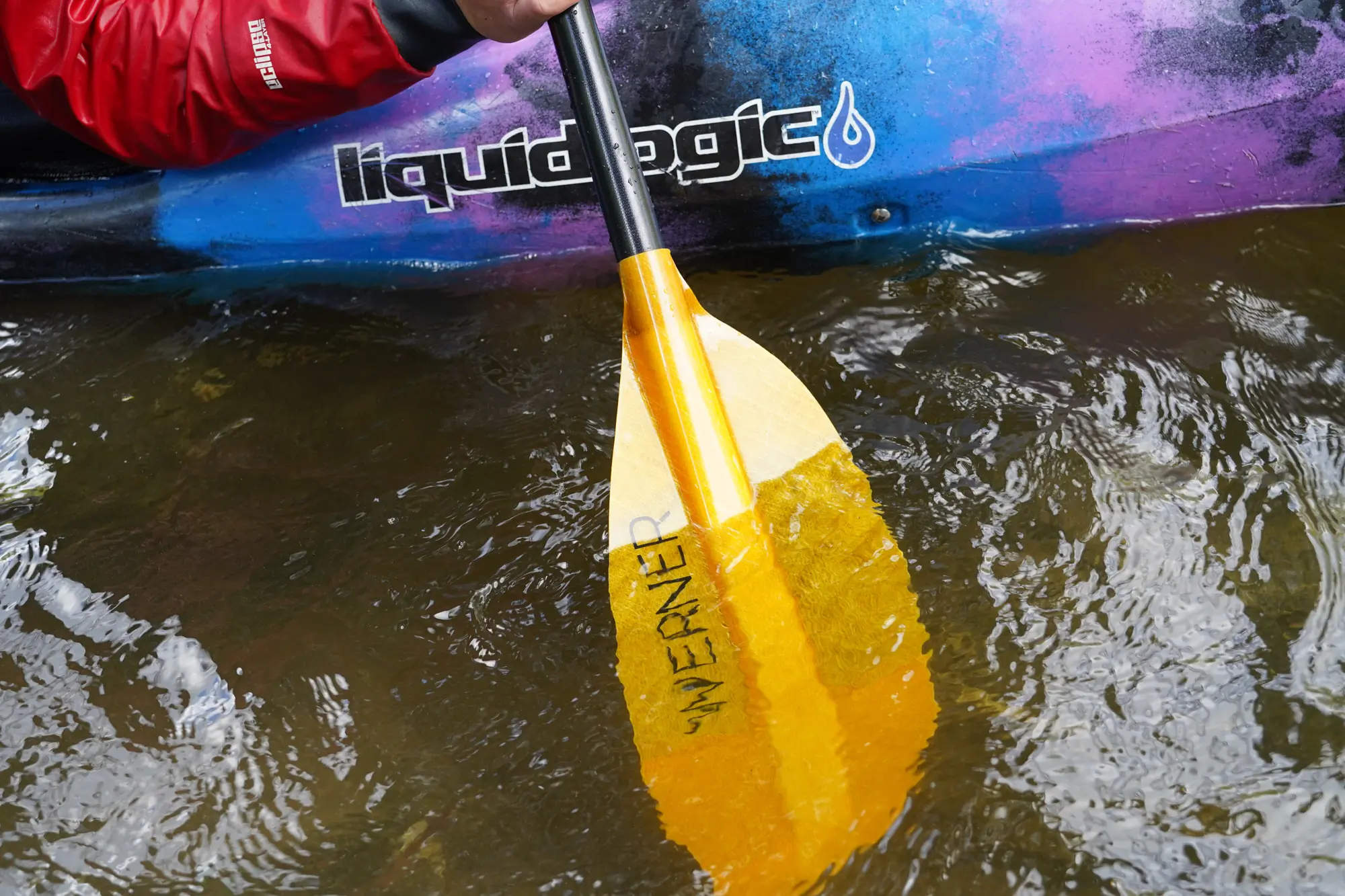 The Sherpa paddle being dipped in the river, showing the blade shape and size