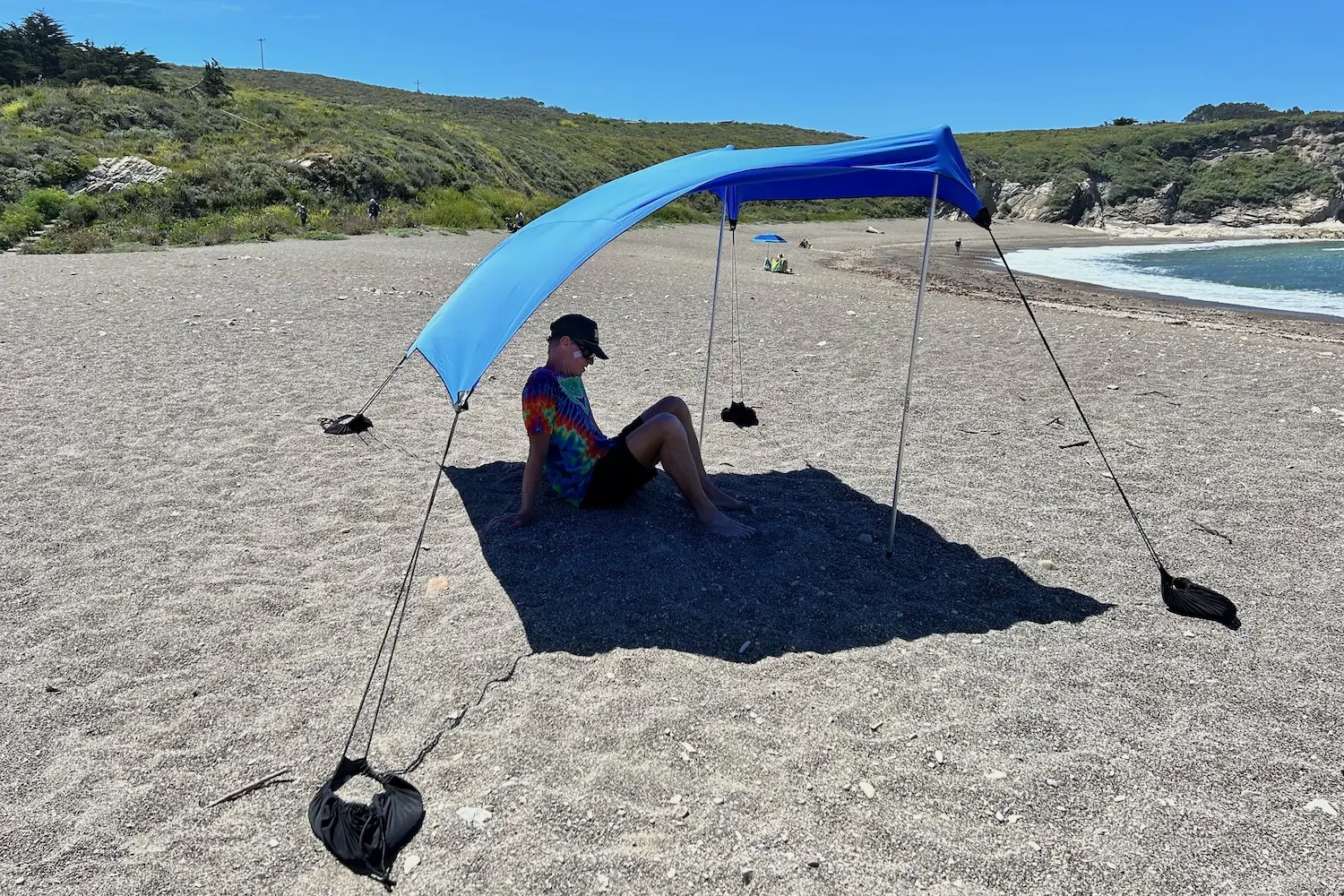 A man sitting under the Neso 1 beach tent at the beach