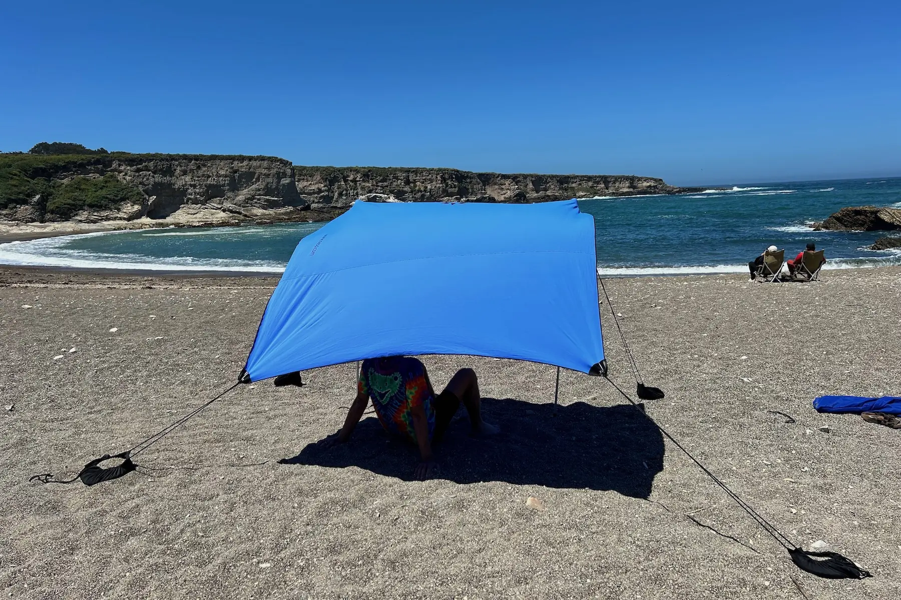 A man sitting under the Neso 1 beach tent and looking out at the ocean