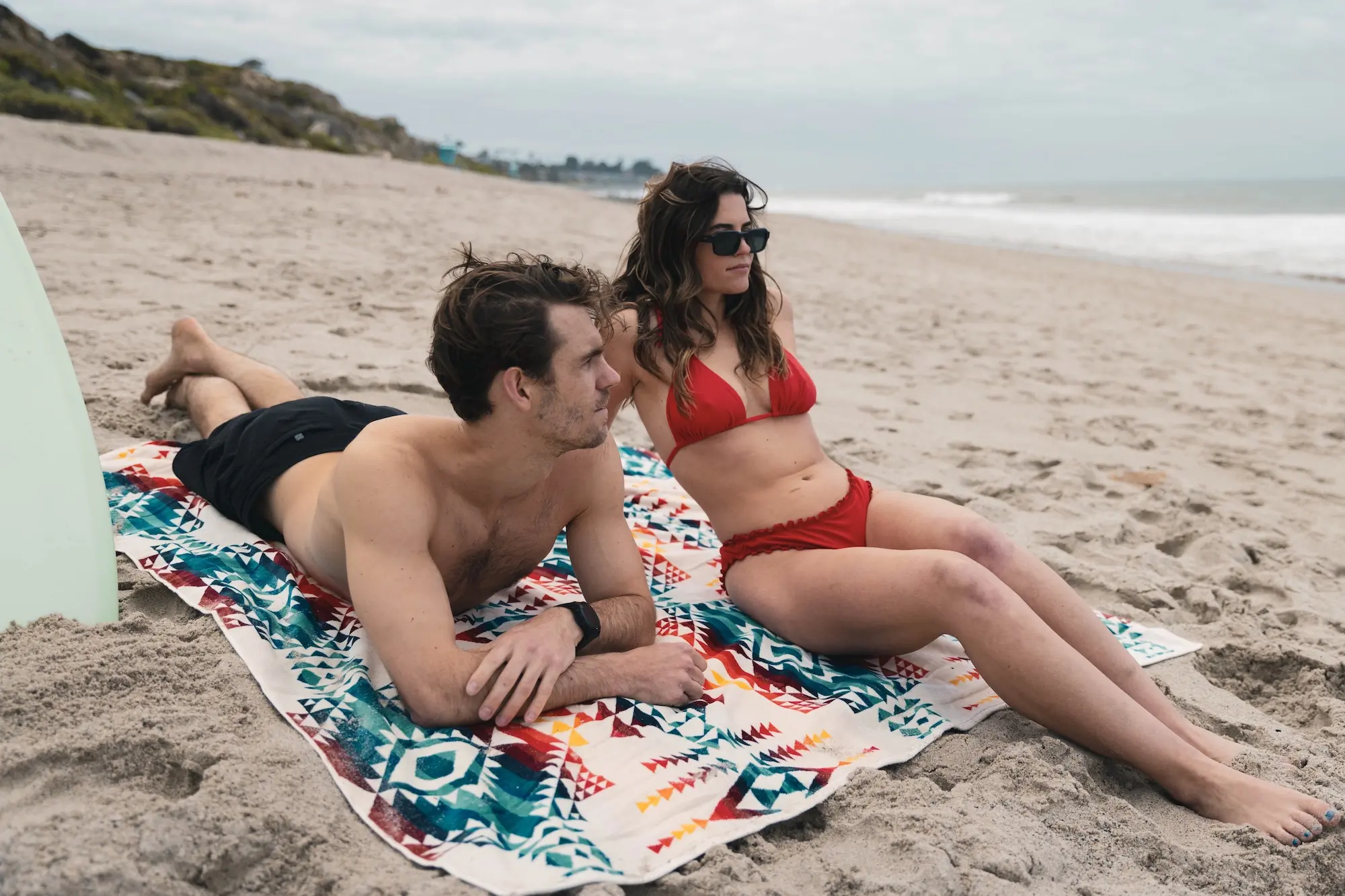 A couple sitting on the Pendleton Towel for Two at the beach