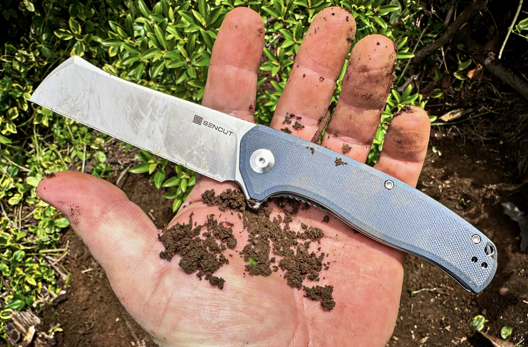 close up of man holding dirty SENCUT Traxler knife