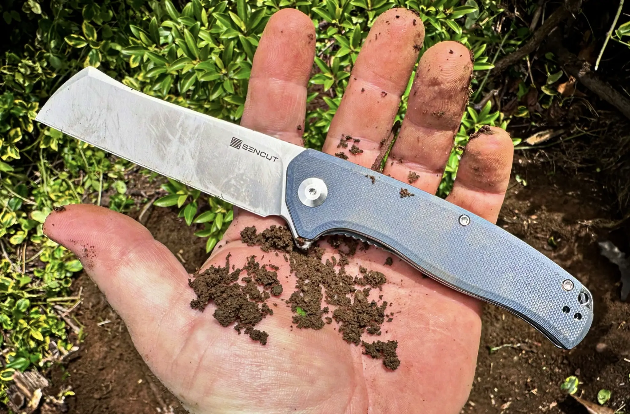 close up of man holding dirty SENCUT Traxler knife