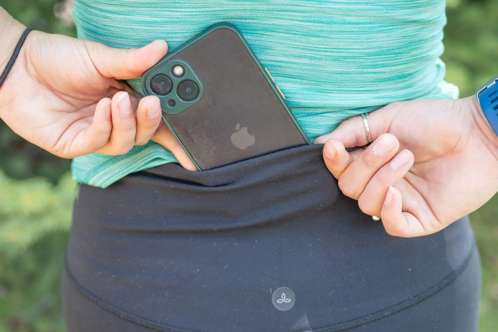 woman placing phone into prana chakara leggings back pocket