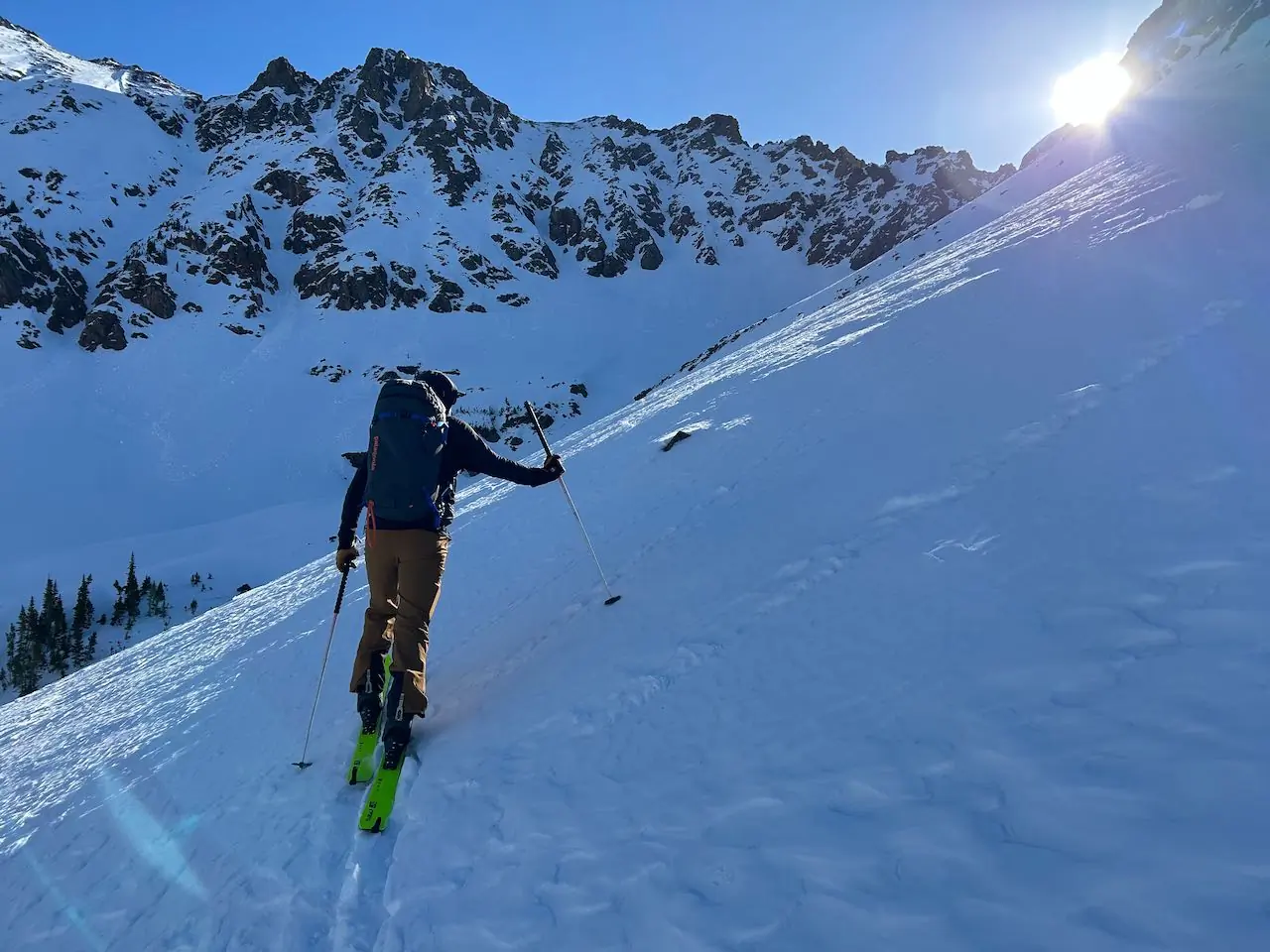 A man, fully equipped for skiing, walks on snow wearing cirque III pants