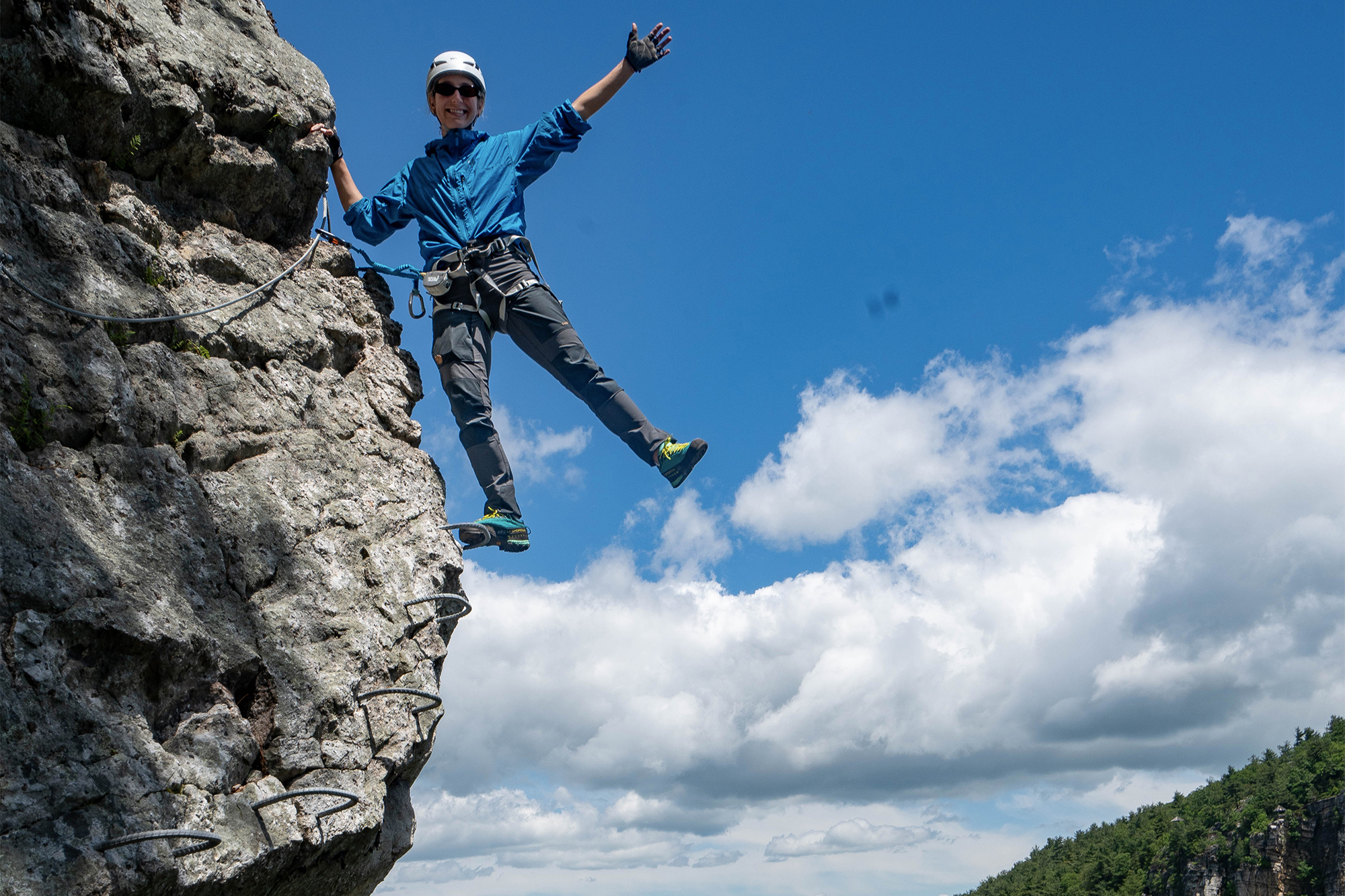 woman hanging on a cliff edge via ferrata