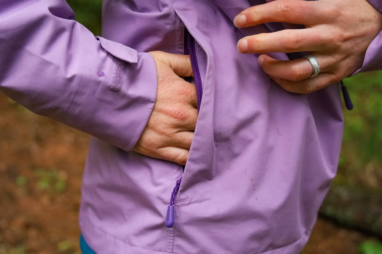 woman placing hand into rain jacket pocket