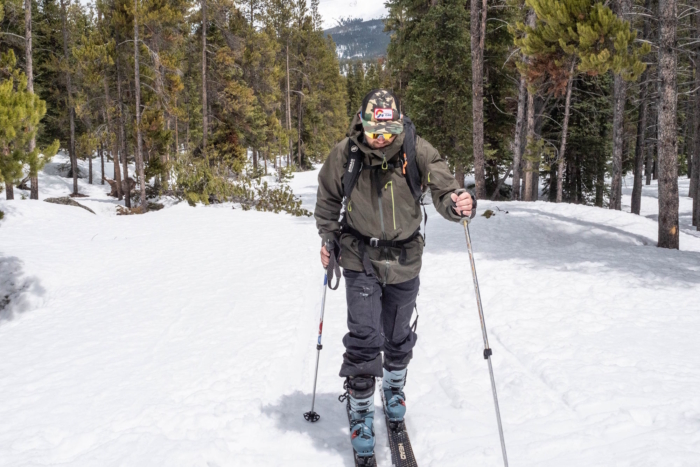Man in Rab Latok Men's Jacket skiing uphill in a snowy forest