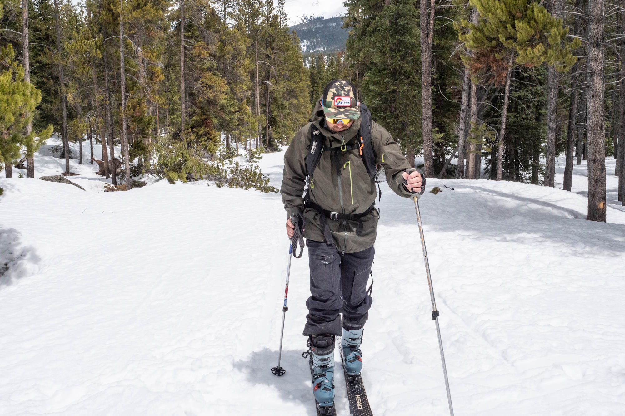 Man in Rab Latok Men's Jacket skiing uphill in a snowy forest