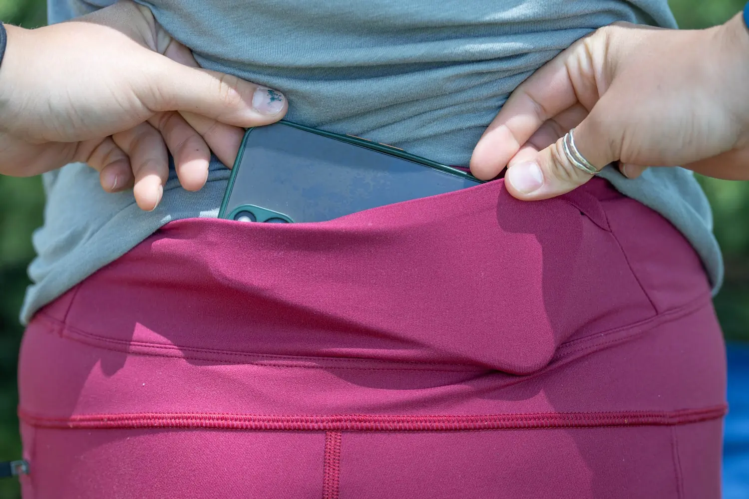 Author placing a smartphone into the back pocket of their stio women's leggings
