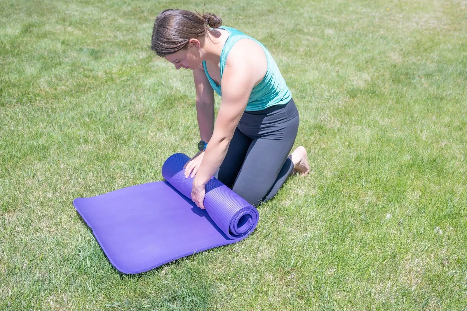 woman in prana chakara leggings rolling yoga mat