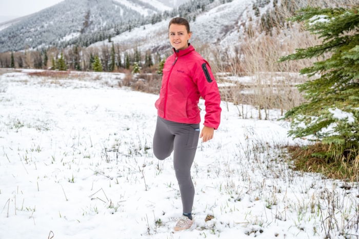 Woman in rabbit defroster tights stretching her leg in a snow-covered landscap