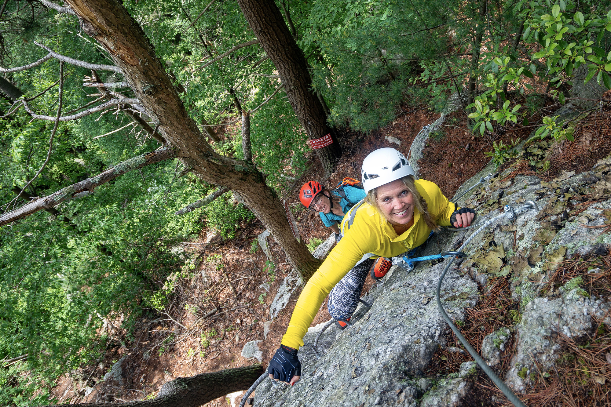 two woman scaling the rugged rocks