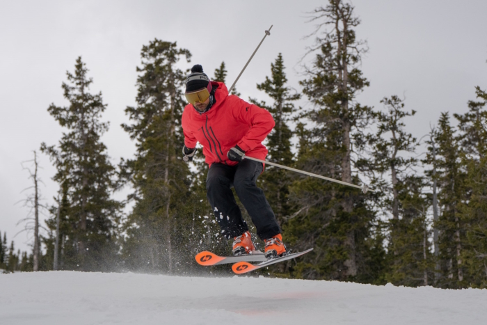 A skier in jacket catches air while skiing