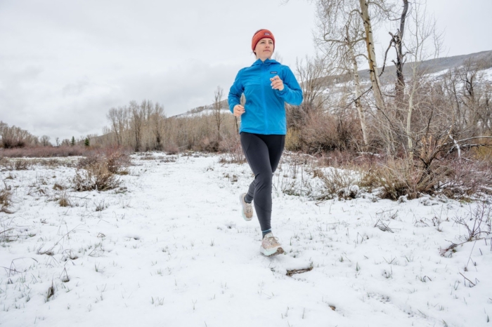 woman running on snow wearing the north face winter warm pro tights