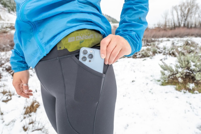 A runner places her phone into one of the spacious hand warmer pockets on the north face winter warm pro tights