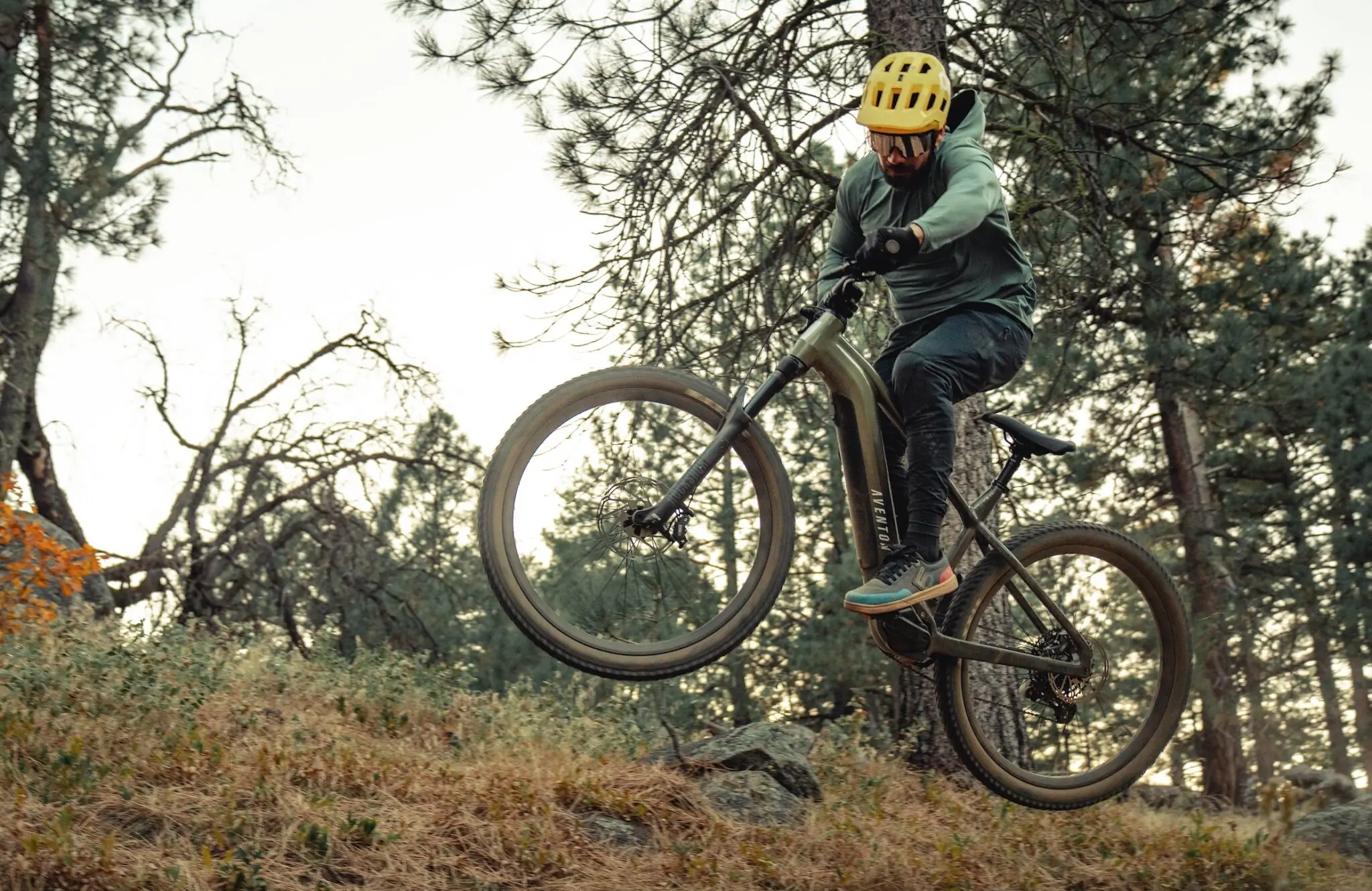 A man jumping and Aventon Ramblas on a mountain bike trail.