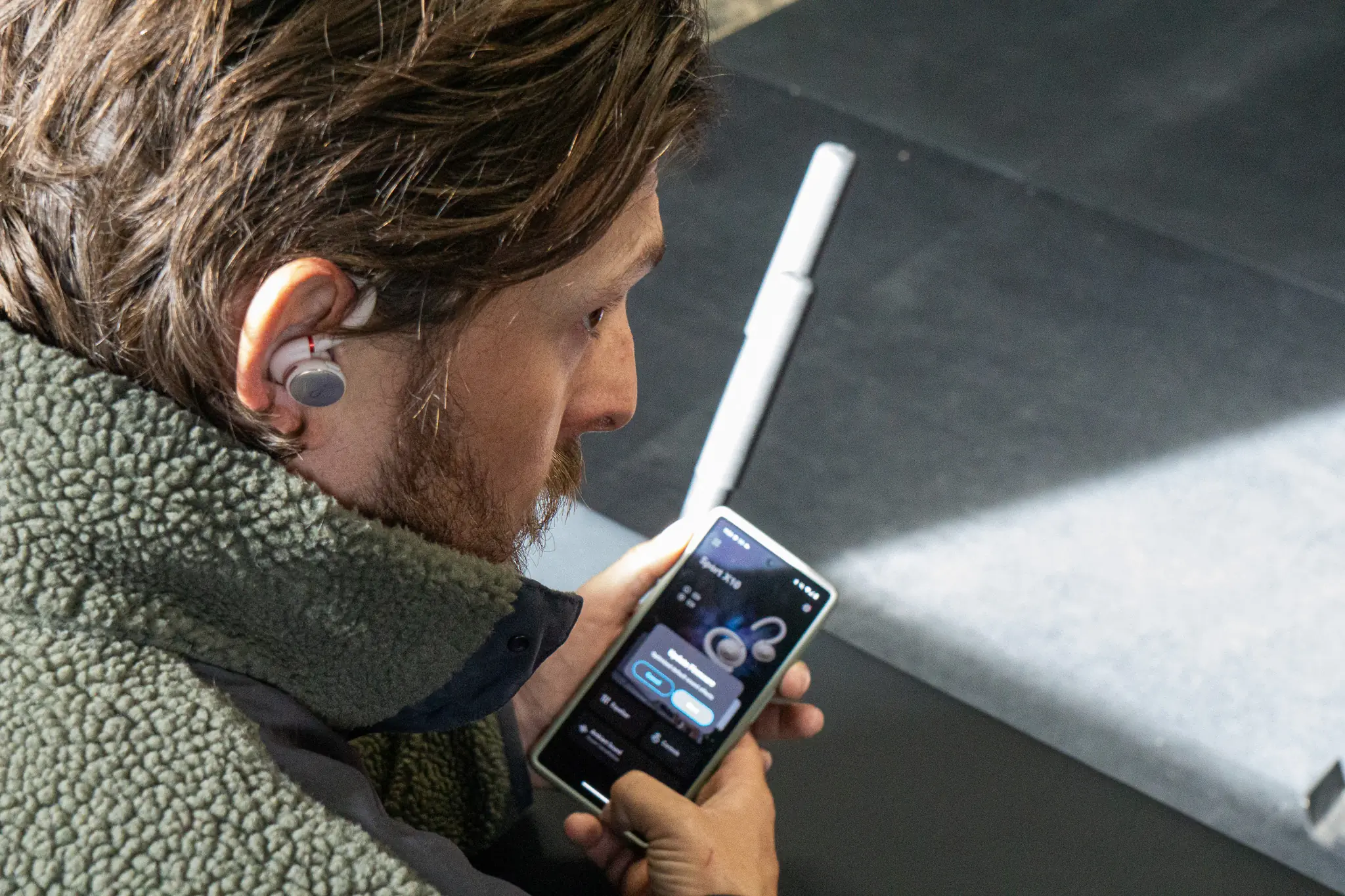a gym-goer uses the anker soundcore app to adjust the EQ settings on the headphones