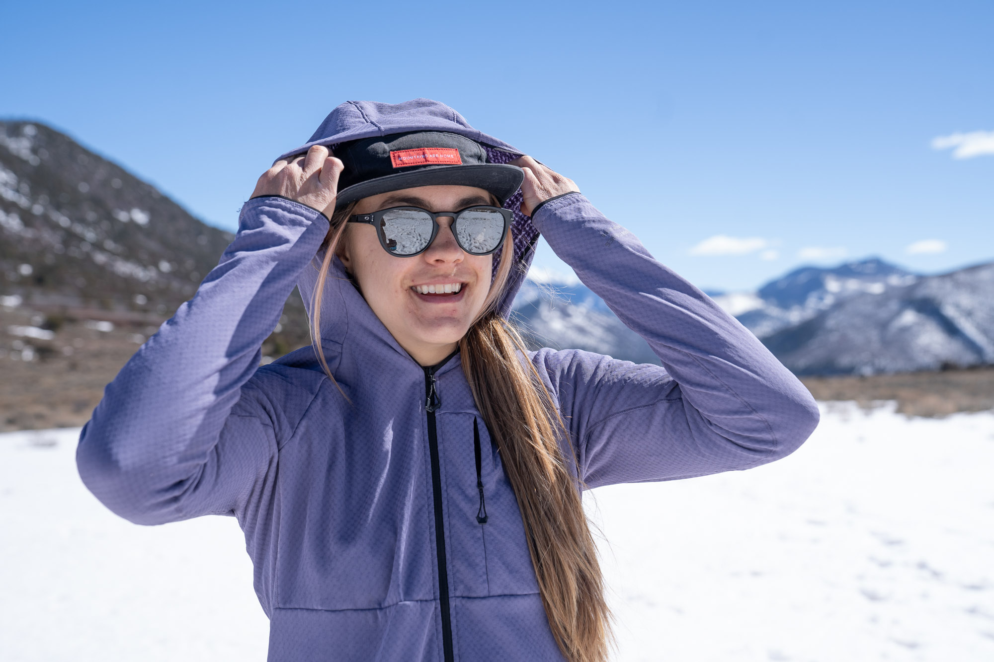 the author adjusts the hood on the futurefleece before a snowy mountain background