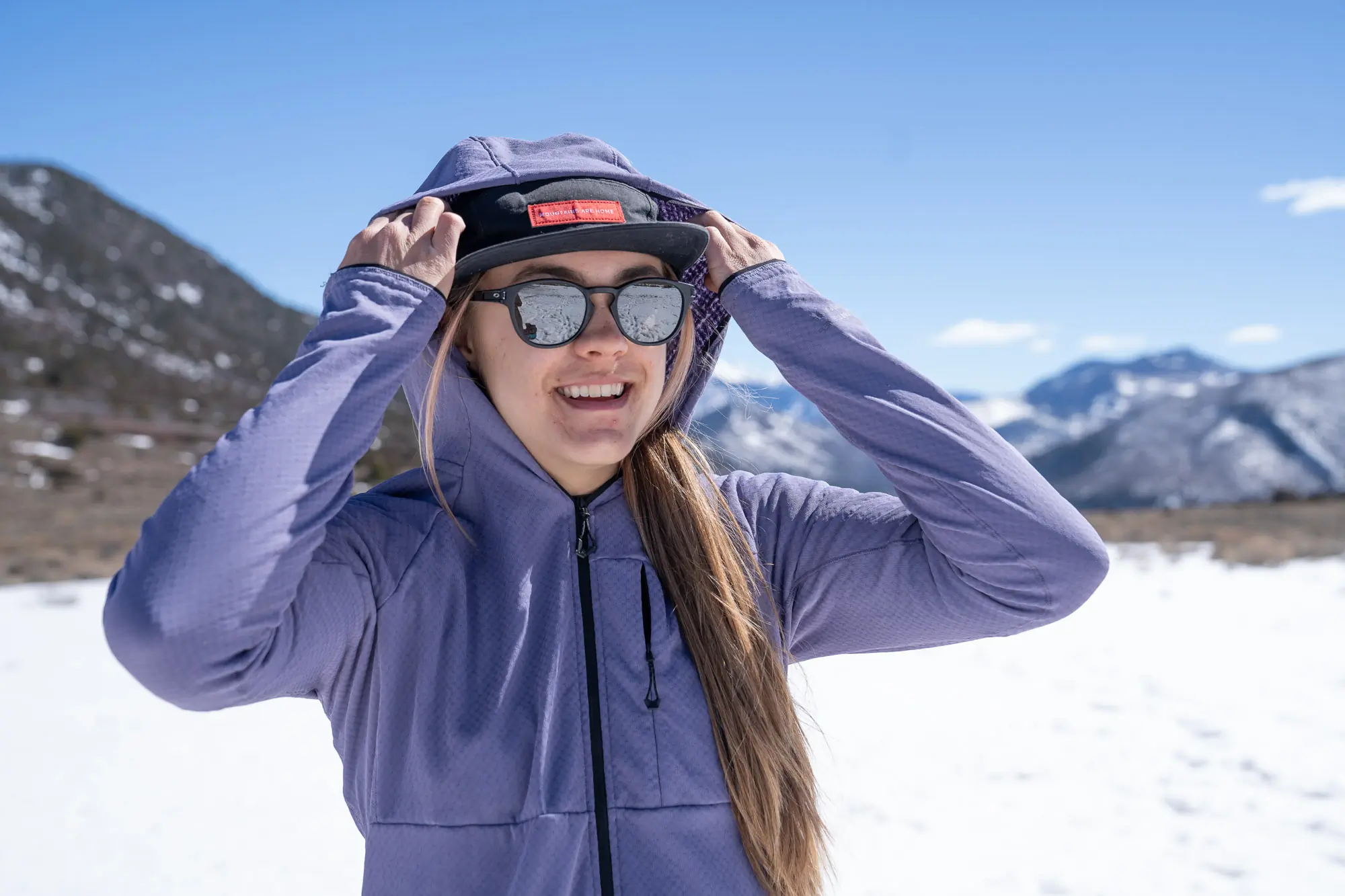 the author adjusts the hood on the futurefleece before a snowy mountain background