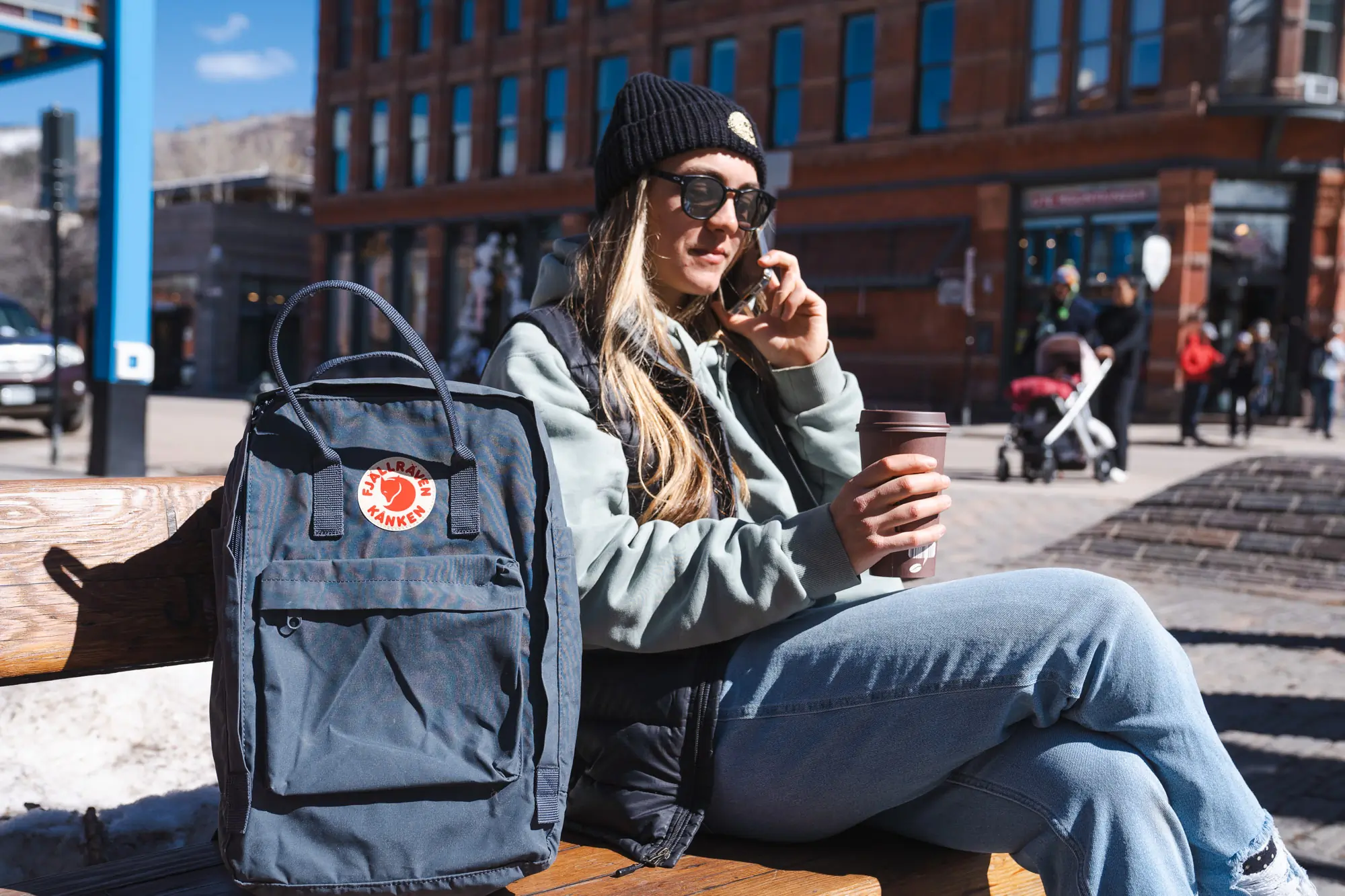 woman sitting next to the Fjallraven Kaken Laptop pack