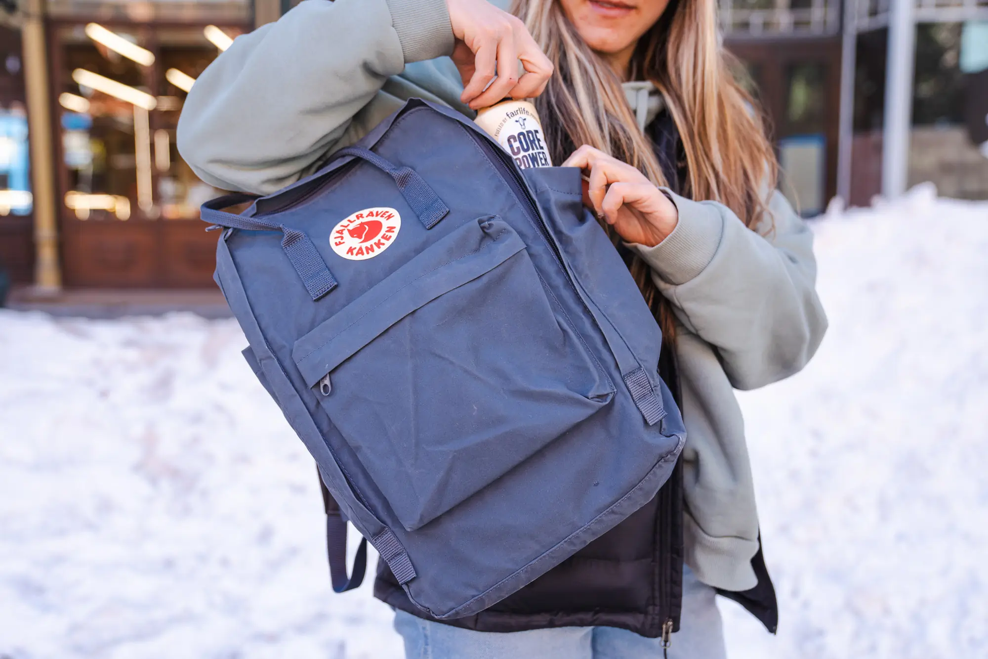woman placing a bottle into the side pocket of the kanken pack