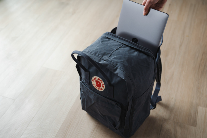 A laptop being placed into the back sleeve of the kanken pack