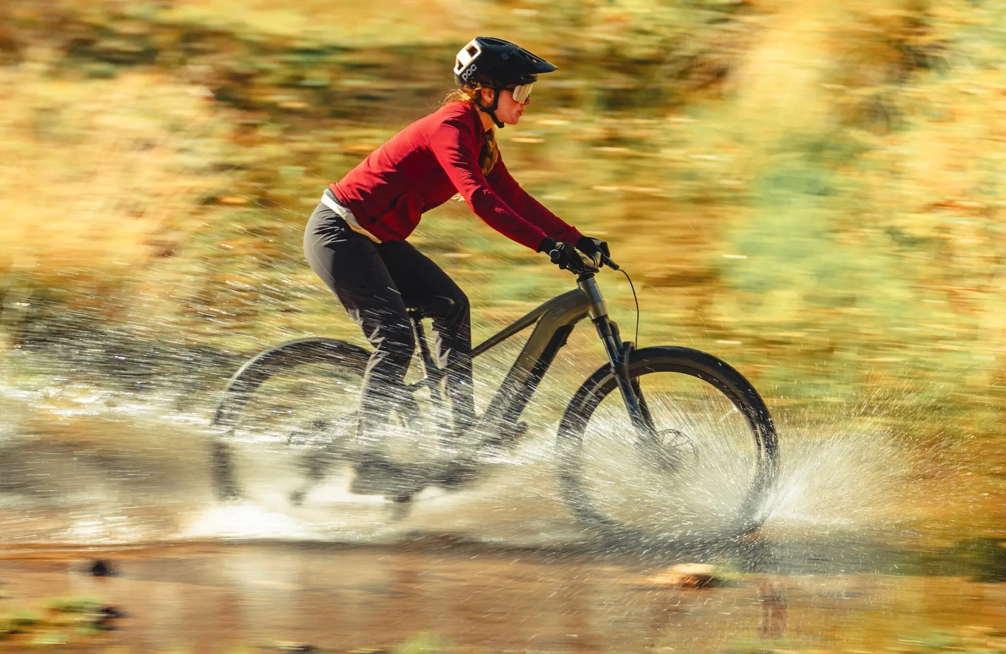 A woman riding and Aventon Ramblas through water.