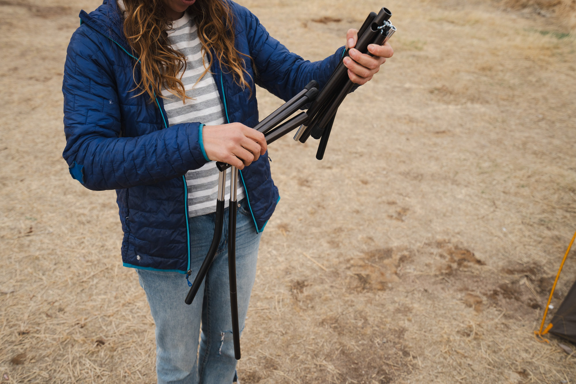 a woman setting the mica basin chair frame together by snapping pole segments into place