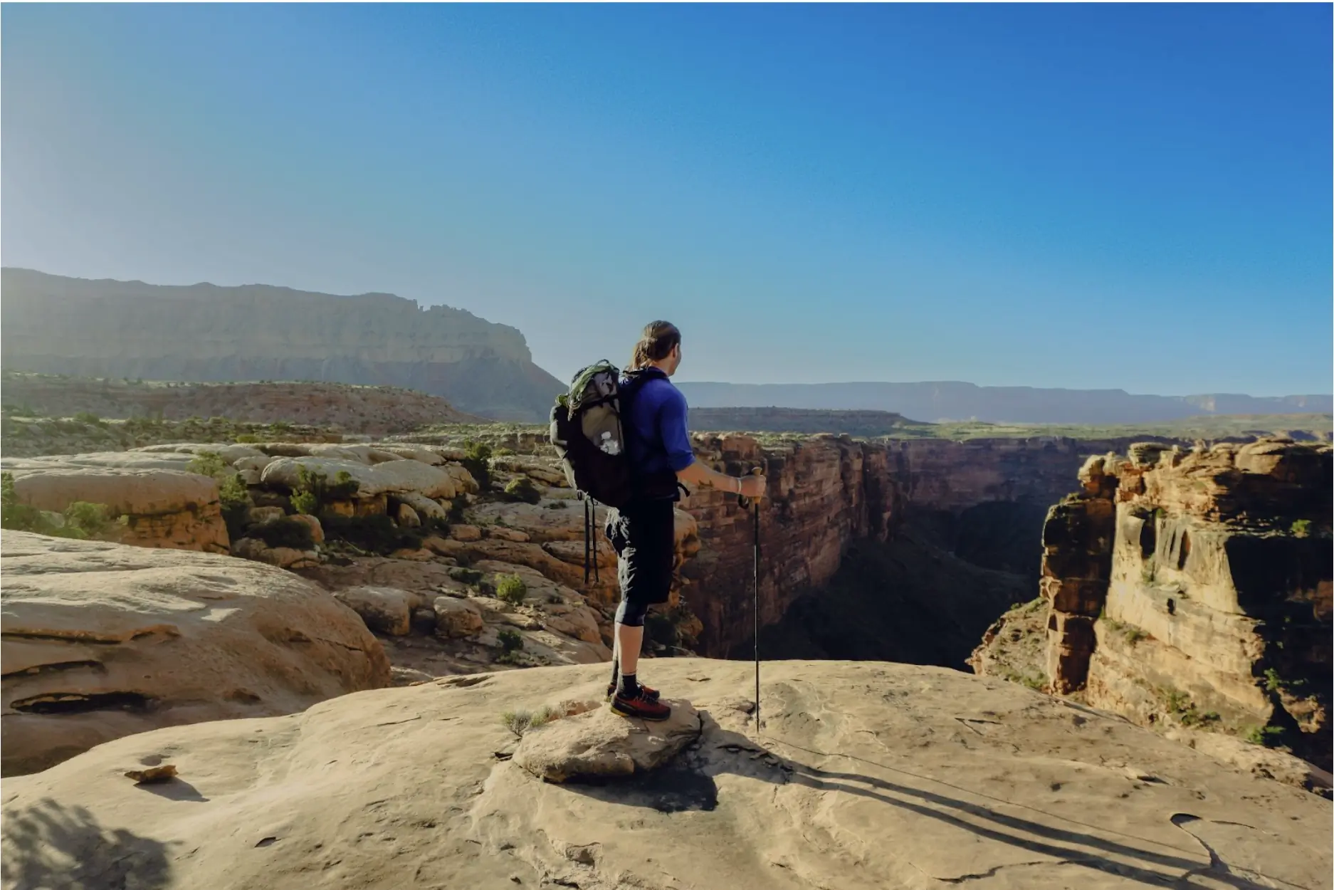 a hiker looks off into the distance over the grand canyon, wearing the ula pack