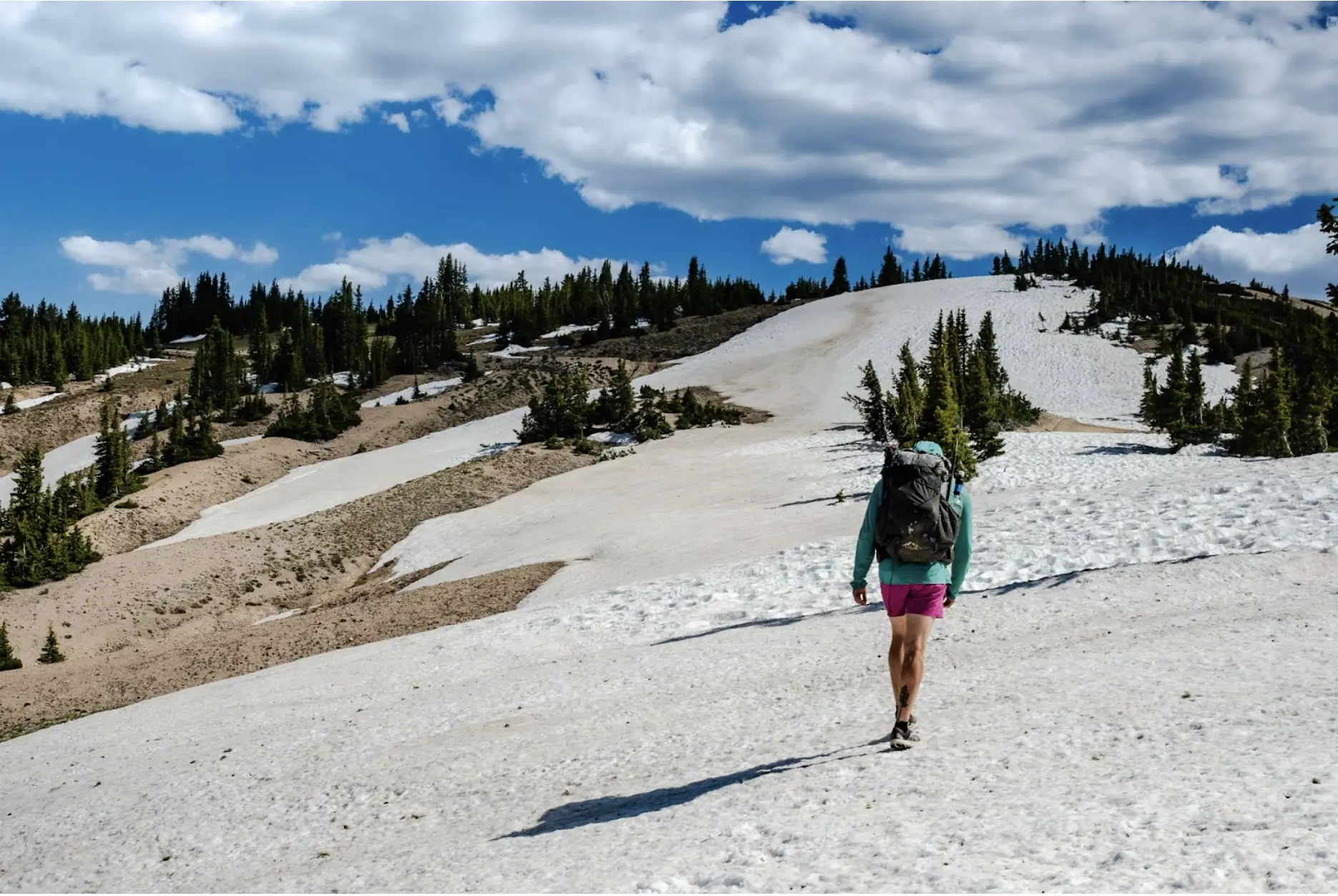 hiking up a snowfield in utah wearing the ULA pack