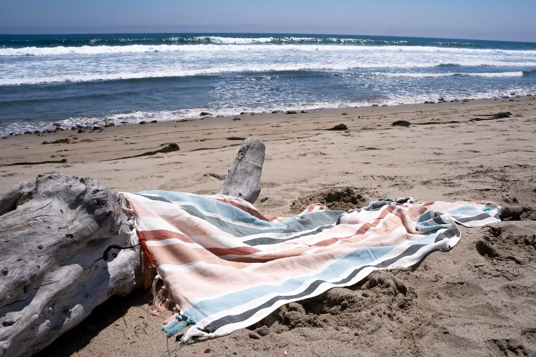 The Slowtide Turkish cotton beach towel on the sand by a surf break in southern California
