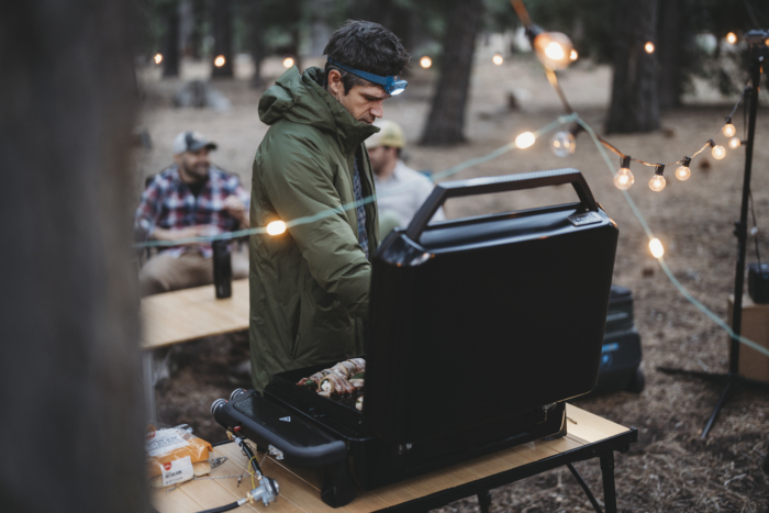 a camp scene with a man cooking dinner on the weber traveler griddle 22