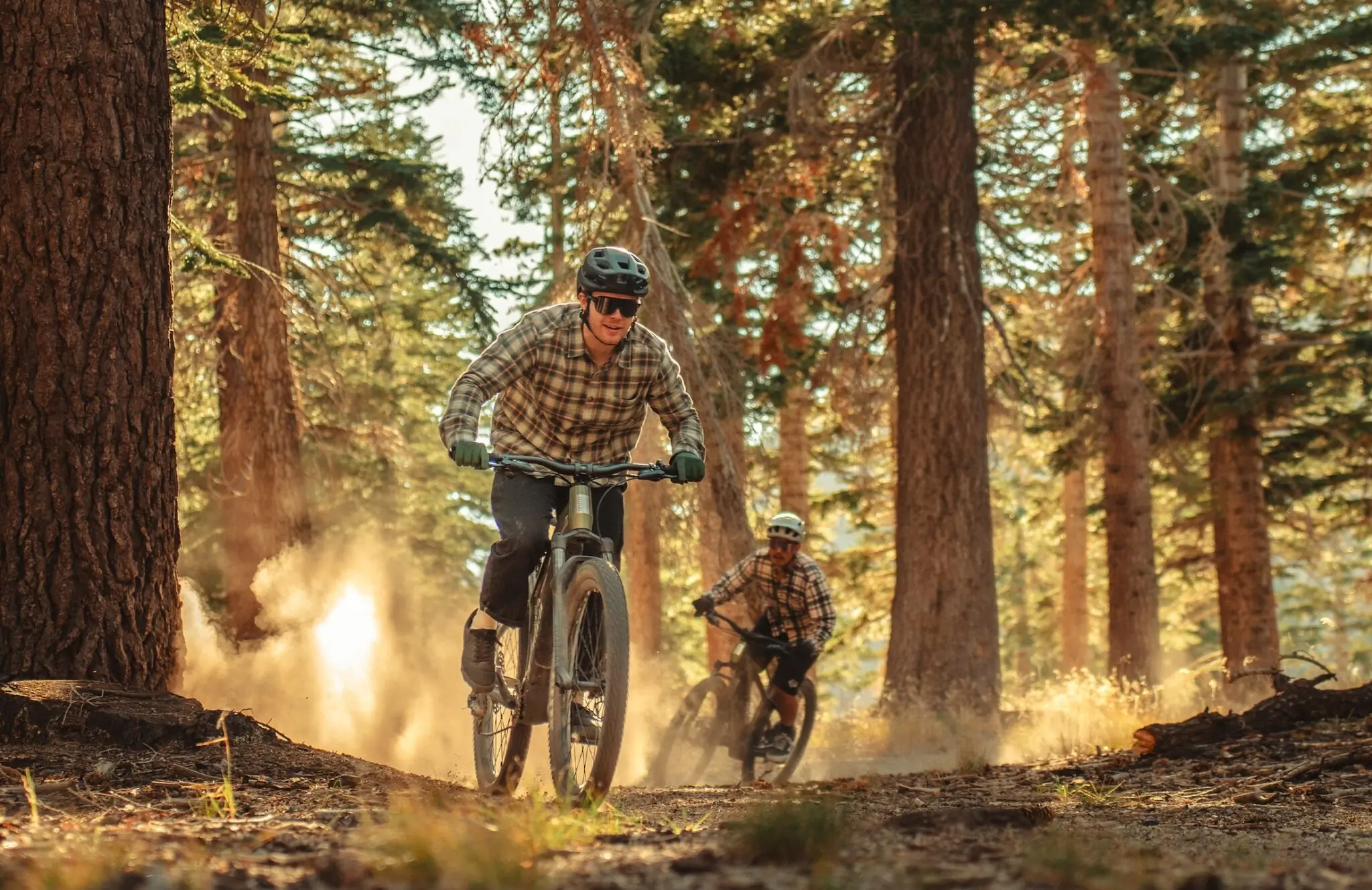 Two men riding Aventon Ramblas e-MTBs on a trail in the woods.