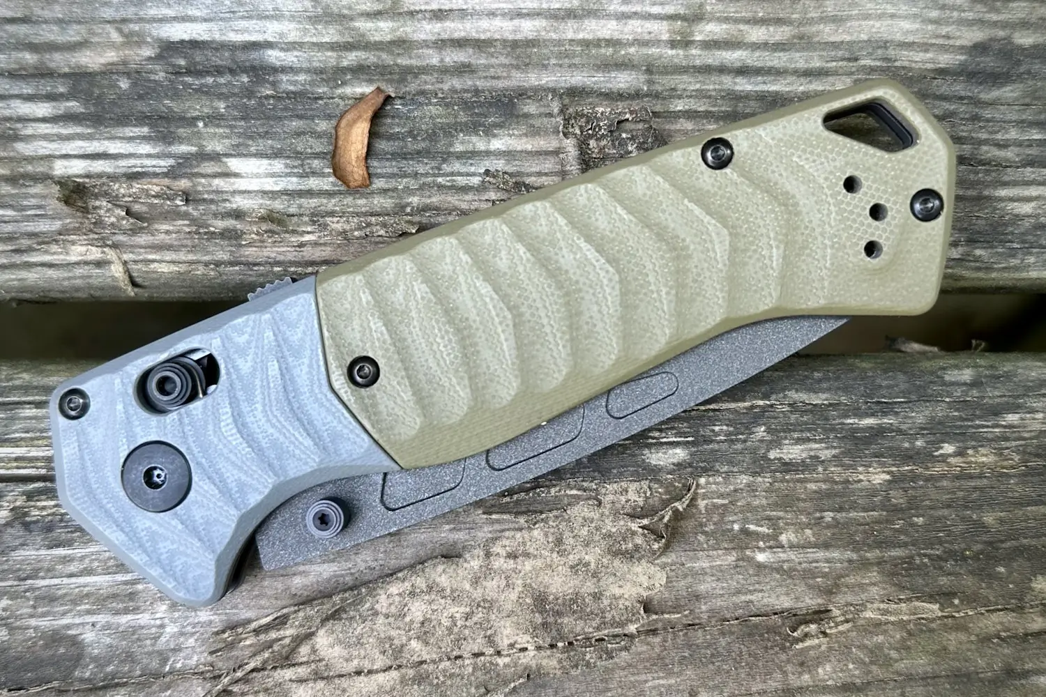 A Benchmade folding knife with a textured grip handle, resting on a wooden planks