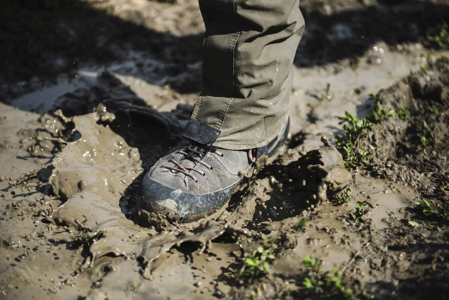 Close-up of a boot splashing through mud during a hike