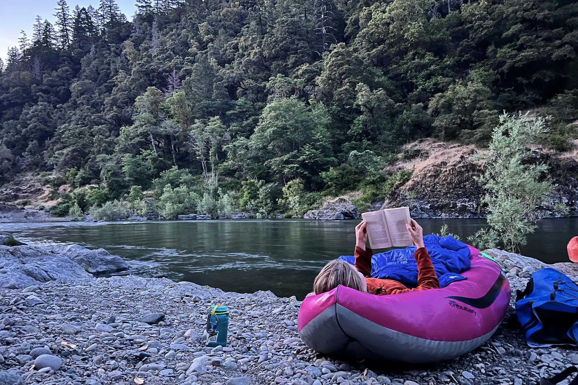 woman laying in aire spud inflatable kayak and reading a book